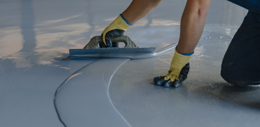 Contractor applying epoxy resin with a trowel to smooth surface in Calgary by Tenmen Construction