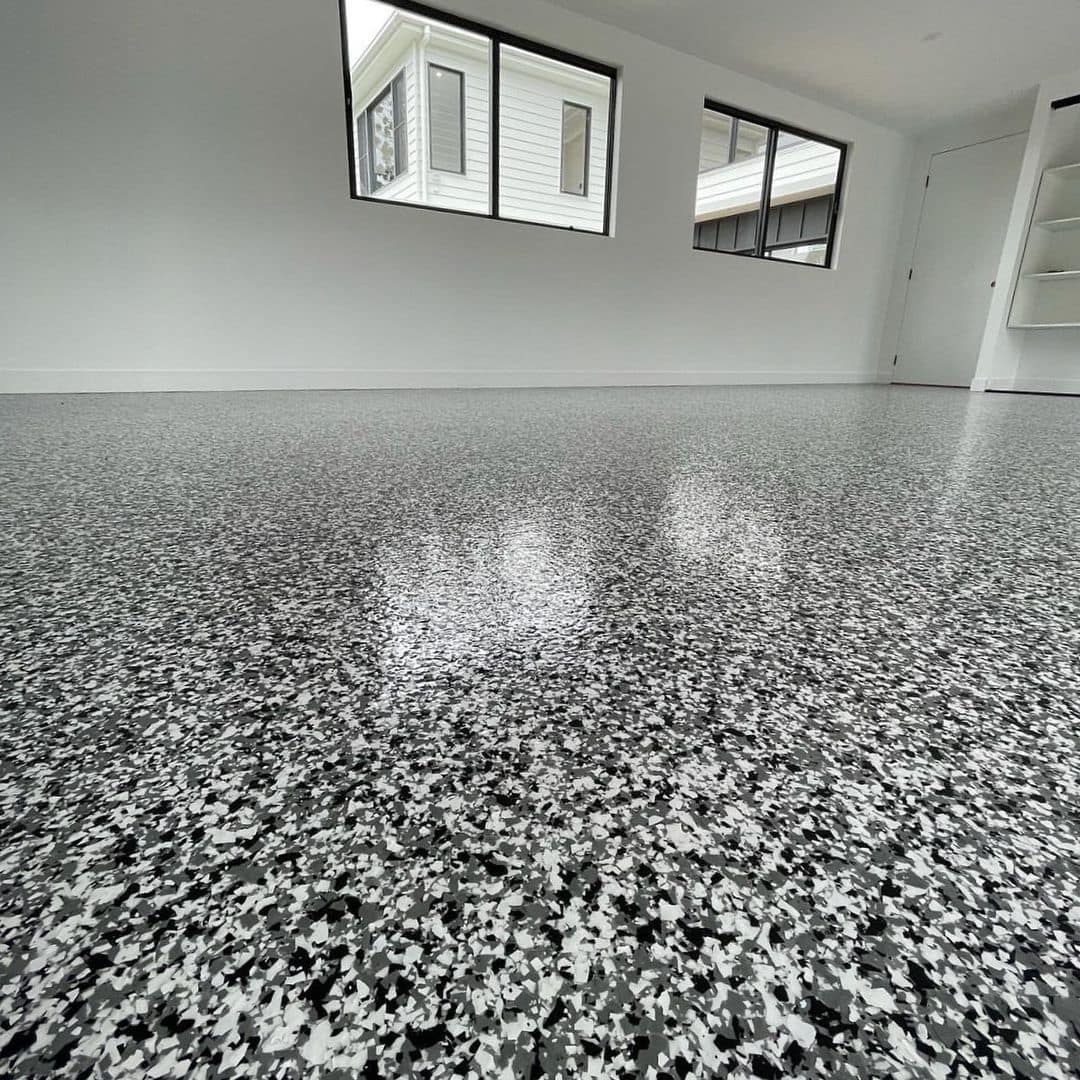 Black, white, and gray flake epoxy flooring in a modern garage.