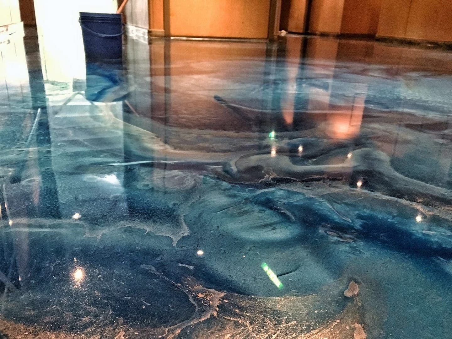 Close-up of glossy blue metallic epoxy floor with reflective finish, applied by Tenmen Construction in Calgary.