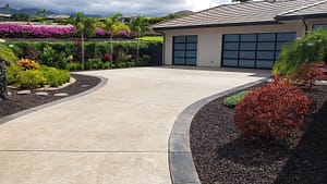Stamped decorative concrete driveway with landscaped garden and tropical plants.