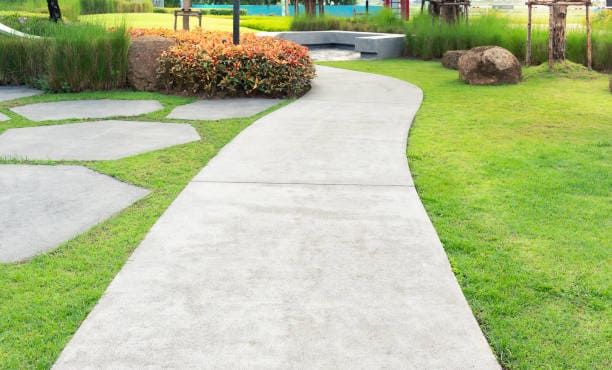 Curved concrete pathway with landscaped garden and decorative stone features.