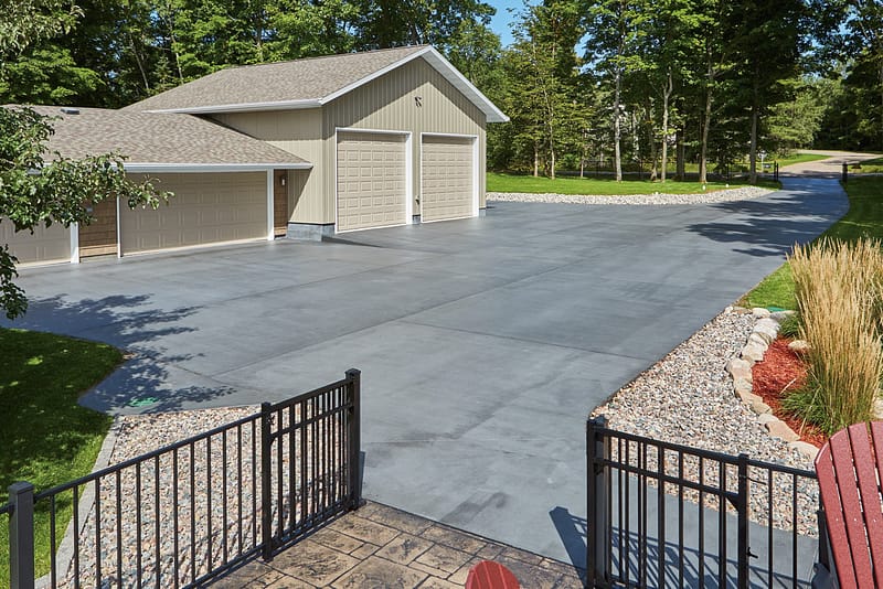 Wide concrete driveway designed for multiple garage entrances with decorative landscaping.